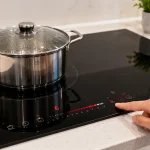 Người dùng thao tác trên bảng điều khiển cảm ứng của bếp điện từ hiện đại